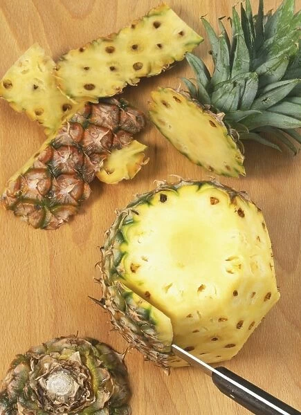 Pineapple skin being cut off the fruit, view from above