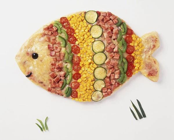 A pizza shaped like a fish with toppings of cheese, ham, sweetcorn, courgette, tomato, green bell pepper, and leaves as decoration