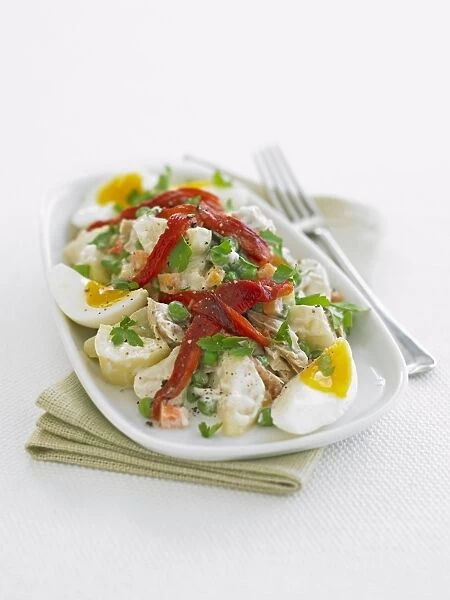 Plate of ensaladilla potato salad with boiled eggs on white background, close-up
