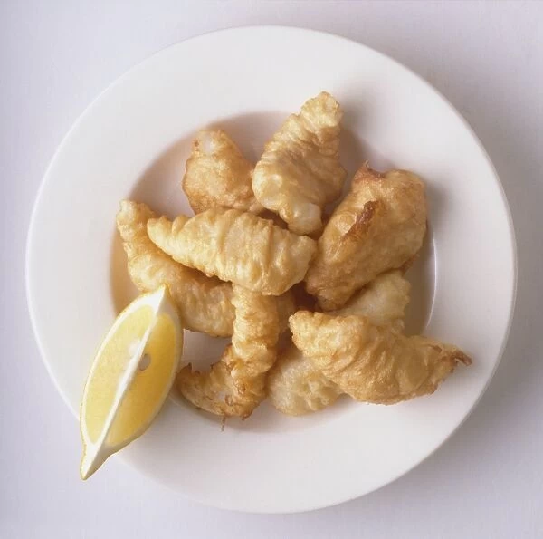 Plate of Filetti di baccala, deep-fried fillets of cod and slice of lemon, a traditional dish from Rome, Italy, view from above
