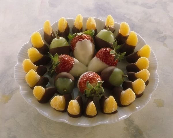 Plate of fruit dipped in chocolate, including tangerines and strawberries