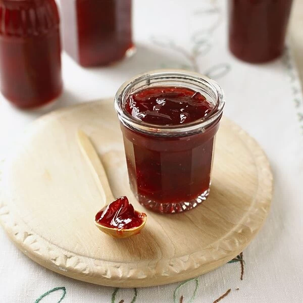 Plum jam in glass and on spoon, close-up