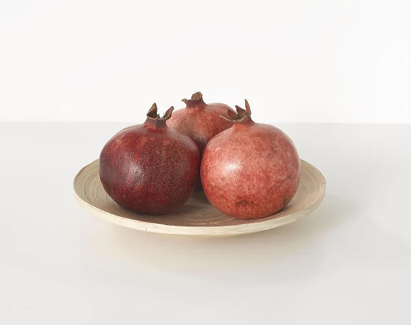 Three pomegranates on white plate