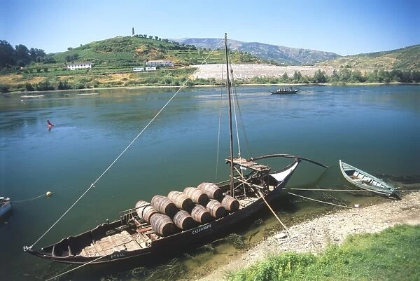 Portugal, Peso da Regua, boat loaded with barrels of port, moored on banks of river