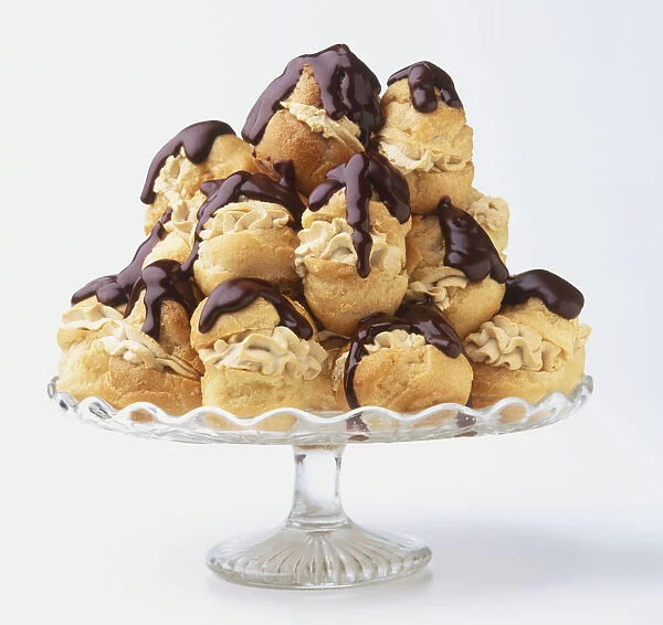 Profiteroles piled on glass cake stand, side view