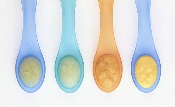 Pureed baby food on four plastic spoons