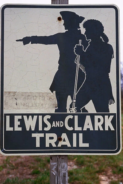 This is a road sign that marks the Lewis and Clark Trail. There is a silhouetted graphic on the sign of the explorers, Lewis and Clark against a white background