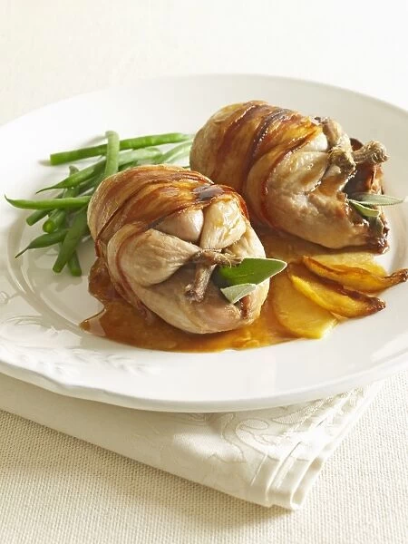 Roast quail wrapped in bacon, with vegetables, on plate, close-up