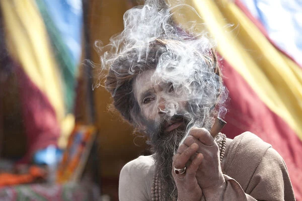 Sadhu, Naga Baba (naked Baba, belonging to the Junna brotherhood) smoking a chilum at the Kumbh Mela in Haridwar, February 2010