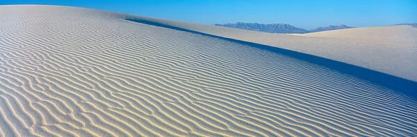 These are sand dunes in the morning. There are lines in the sand that form a pattern from the wind