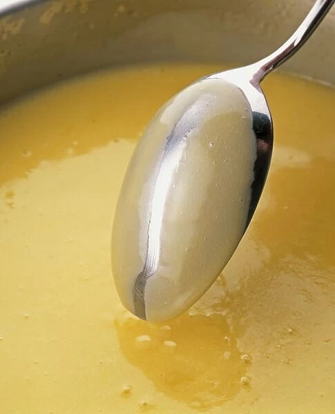 Sauce thickened with butter, in a saucepan and coating the back of a metal spoon, close-up