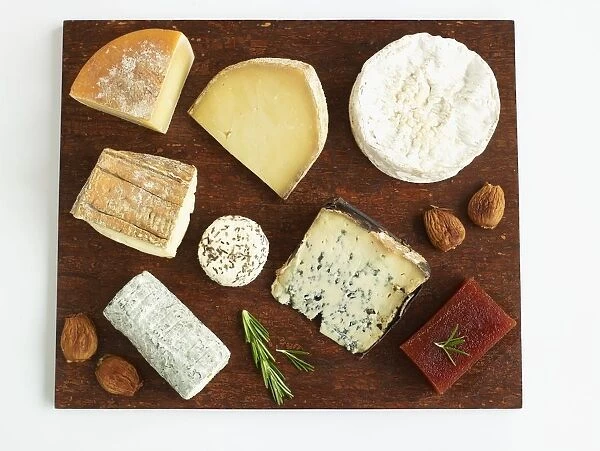 Selection of cheeses on wooden cheese board, including Berkswell, Camembert, Innes Button, Saint-Maure de Tourain, Taleggio, Valdeon, Cornish Yarg