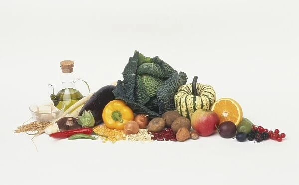 Selection of vegan diet foods, including fresh fruit and vegetables, olive oil, seeds and pulses, side view chilli, aubergine, pepper, cabbage, pumpkin, apple, orange, potato, plum and berries