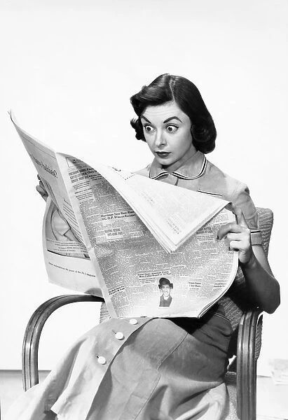 Shocked woman reading newspaper