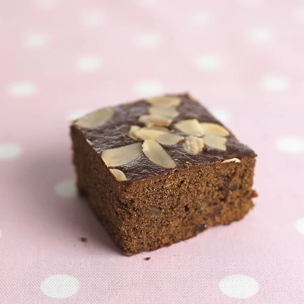 Slice of chocolate cake topped with walnuts on polka dot tablecloth, close-up