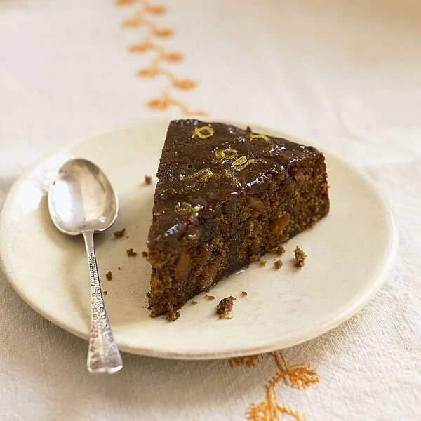 Slice of ginger fruitcake, on a plate with a spoon