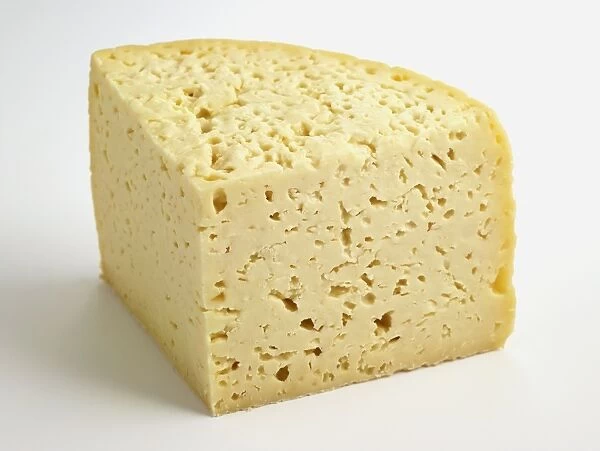 Slice of semi-soft Italian Pannerone cows milk cheese showing multiple holes