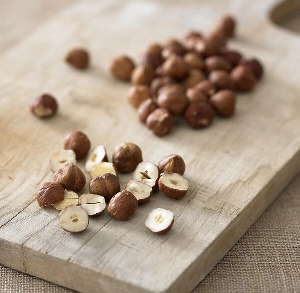 Whole and sliced hazelnuts on chopping board