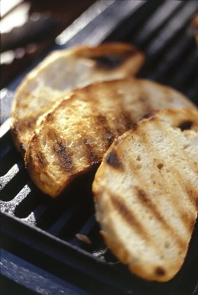 Three slices of grilled bread, on barbecue grill, close-up