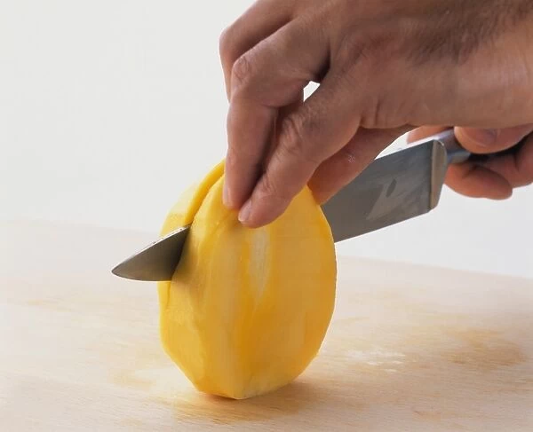 Slicing peeled mango in half, close-up