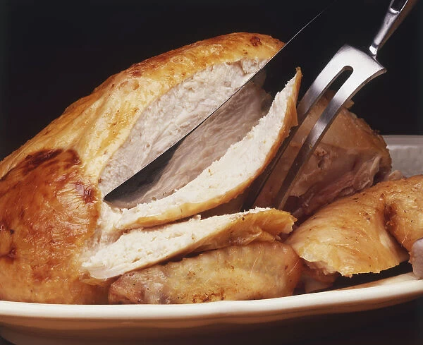 Slicing turkey breast, using fork and knife, close-up