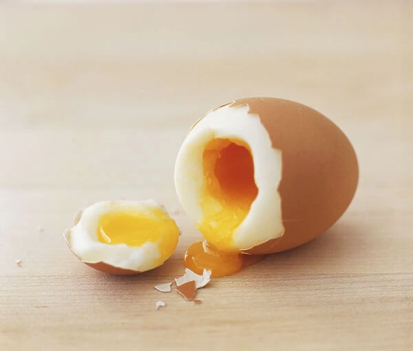 Soft-boiled egg with section removed and yolk spilling out, close up