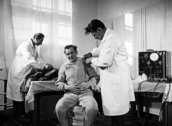 Soviet cosmonaut gherman titov being helped in the putting on of his space suit in preparation for his flight in the vostok 2 mission, 1961, a still from the documentary film to the stars again