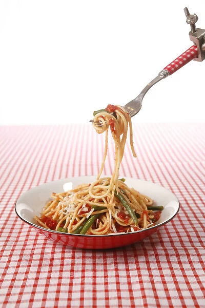 Spaghetti with vegetables in bowl and on fork