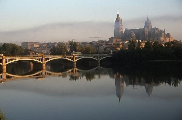 Spain, Castile and Leon, Salamanca, Enrique Esteban bridge over Tormes River with reflection of Old and New Cathedrals