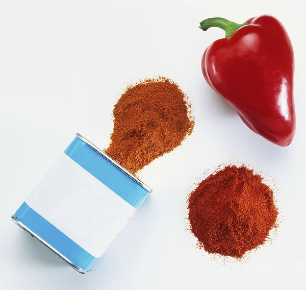 Spanish Pimenton spilling out of a can, a pile of Hungarian paprika and a fresh red pepper