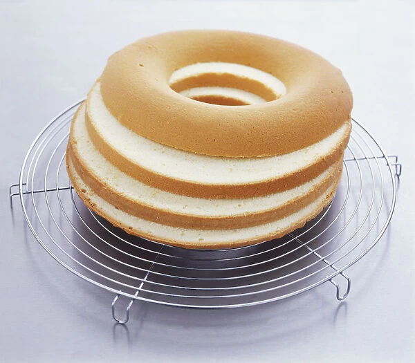 Sponge cake cut into four layers resting on a wire rack