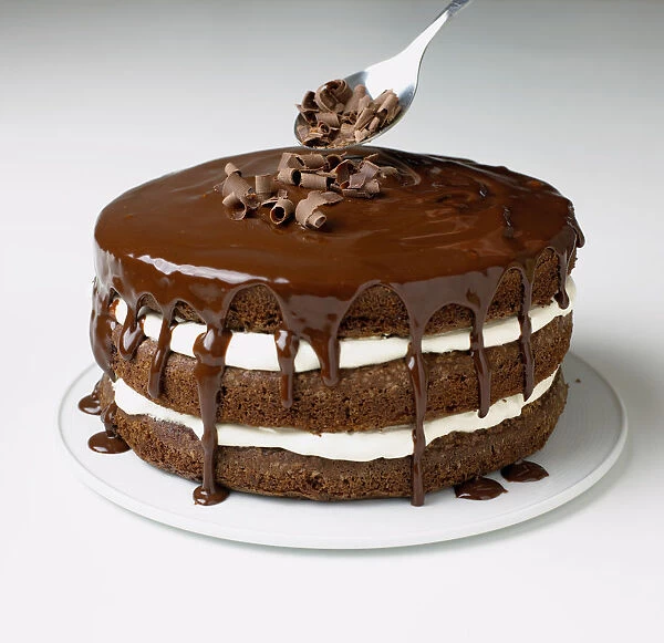 Sprinkling chocolate curls onto chocolate and cream cake