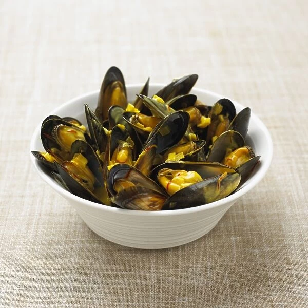 Steamed mussels with saffron sauce in bowl, close-up