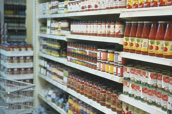 Supermarket shelves containing bottles of organic sauces, tinned vegetables and other goods