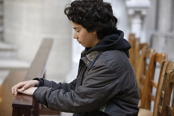 Teenager praying in Notre Dame of Bayeux cathedral