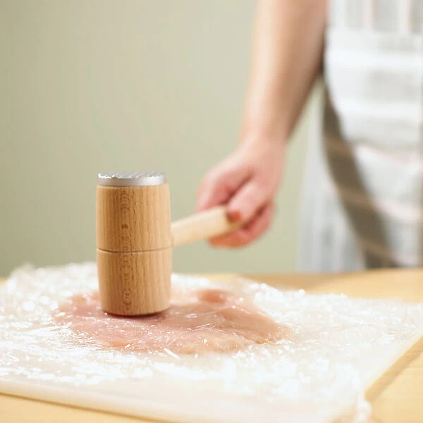 Tenderising chicken fillet with mallet, close-up