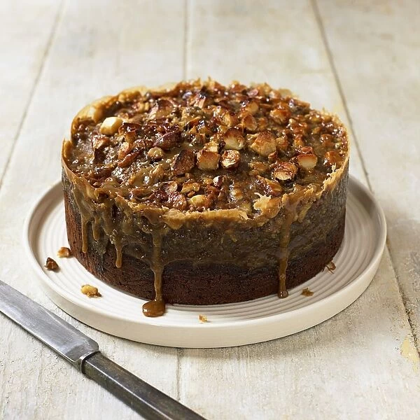 Toffee banana cake topped with nuts, knife nearby