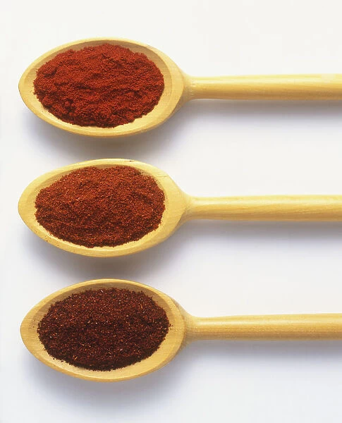 Types of powdered pepper on three wooden spoon