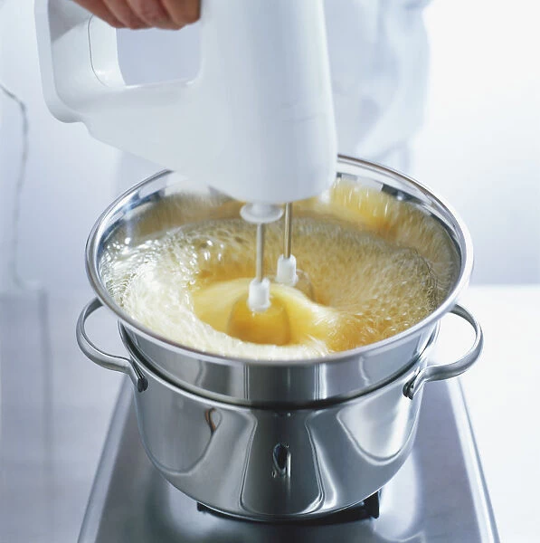 Using an electric whisk to mix eggs, sugar and honey in a heatproof bowl