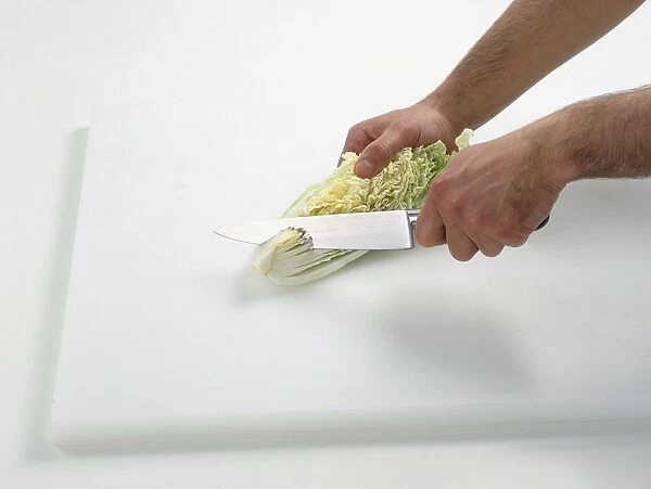 Using kitchen knife to cut core from Chinese cabbage on chopping board