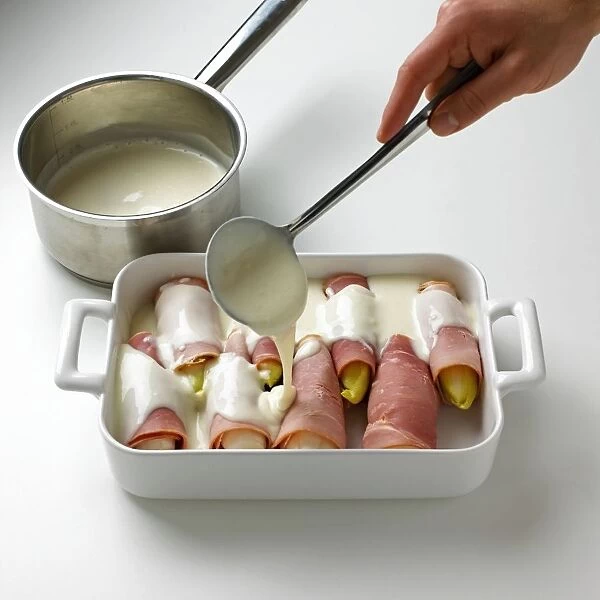 Using ladle to pour bechamel sauce over chicory gratin wrapped in ham in dish