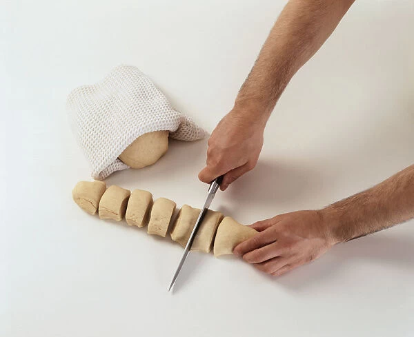 Using large kitchen knife to cut long bread dough into small slices