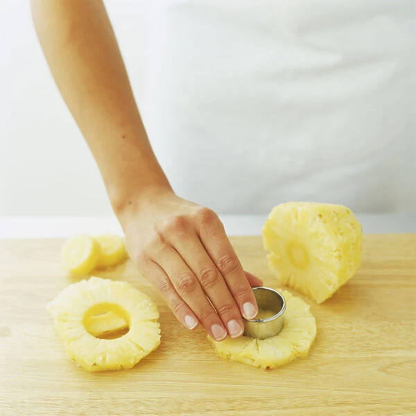 Using a pastry cutter to cut out the centre of pineapple slices
