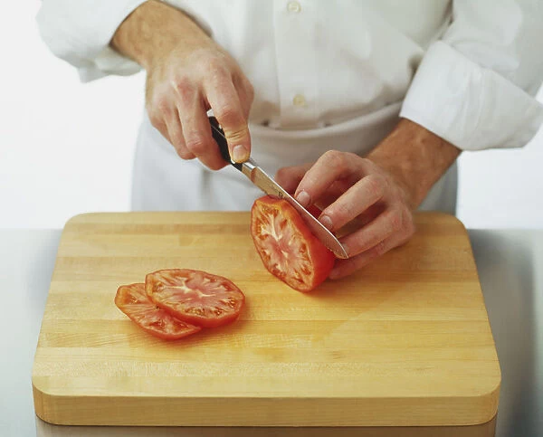 Using a serrated knife to cut tomato into slices