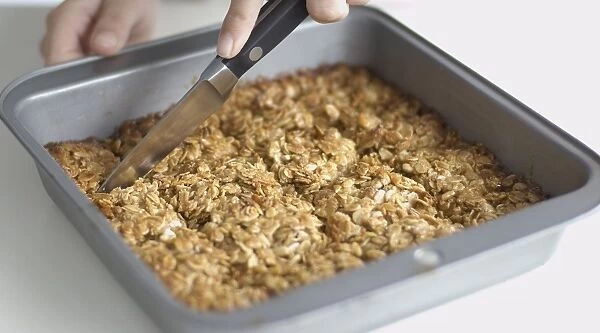 Using small kitchen knife to cut oatmeal flapjacks