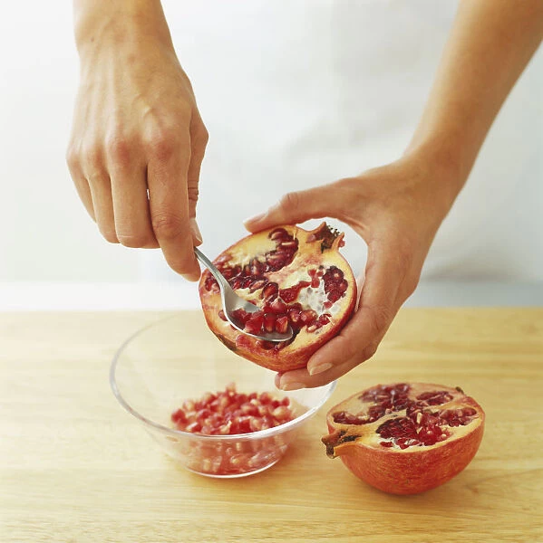 Using spoon to remove pomegranate seeds