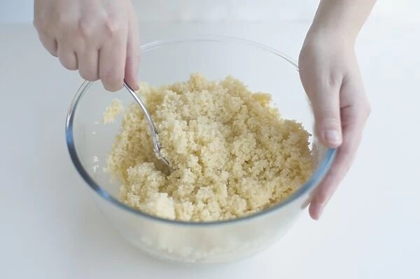 Using spoon to stir cous-cous in mixing bowl