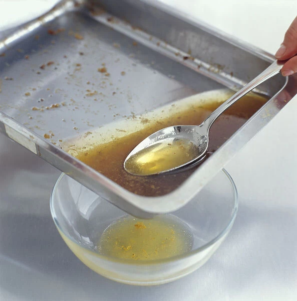 Using tablespoon to remove fat from roasting pan into glass bowl