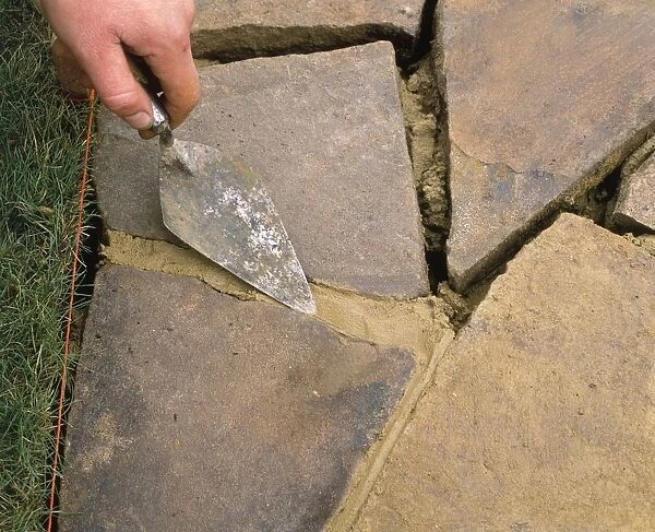 Using a trowel to bevel mortar between crazy paving, close-up