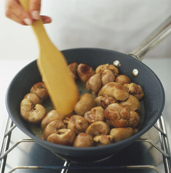 Veal kidney being fried in oil in a heavy frying pan